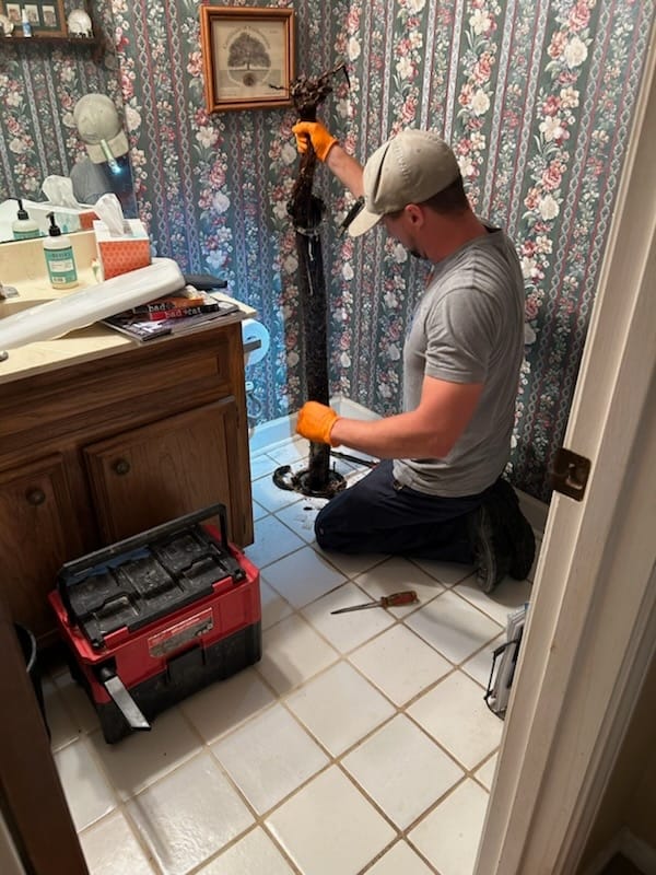Plomero de Rooter-Man of Austin trabajando en el baño de un cliente, foto real